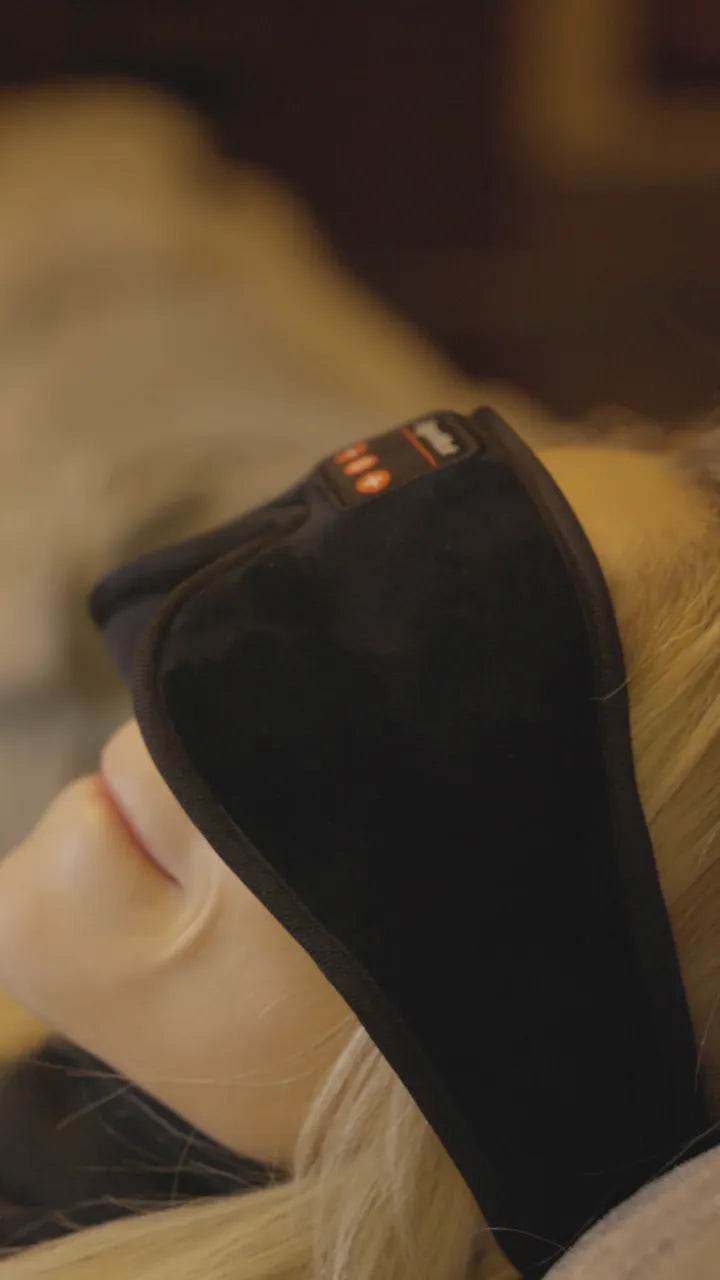 A woman lying back on a sofa with the mask on, mid-session